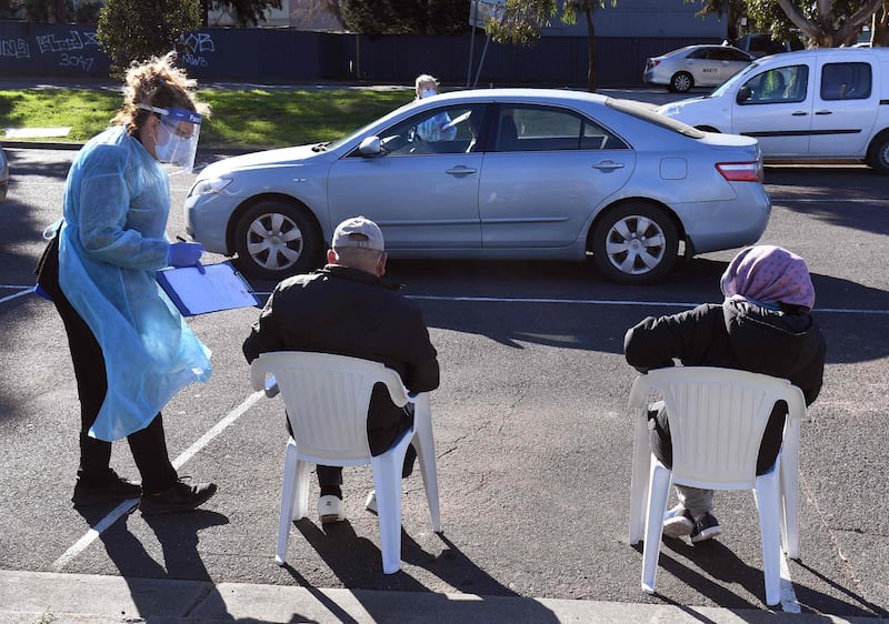 People wait in chairs and cars during testing for the COVID-19 coronavirus at a drive and walk through pop-up venue in Melbourne on July 1, 2020. Around 300,000 people in Melbourne were preparing to return to lockdown under the threat of fines and arrest July 1 as Australia’s second biggest city attempts to control a spike in virus cases.
 / AFP / William WEST
