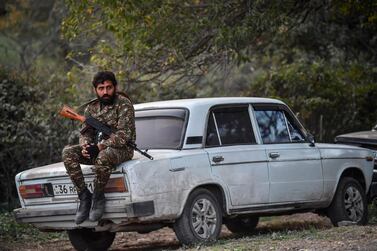 A volunteer fighter sits on a car in a village south-east of Stepanakert on October 23, 2020, during the ongoing fighting between Armenian and Azerbaijani forces over the breakaway region of Nagorno-Karabakh. The Russian president said on October 22 that the death toll was nearing 5,000 since full-scale fighting reputed last month, in the worst flare-up in the disputed Nagorno-Karabakh region in more than two decades. / AFP / ARIS MESSINIS