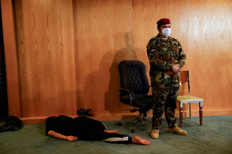 A soldier stands next to a sleeping supporter of Shiite cleric Moqtada Al Sadr during a sit-in, inside the parliament building in Baghdad, Iraq. Reuters
