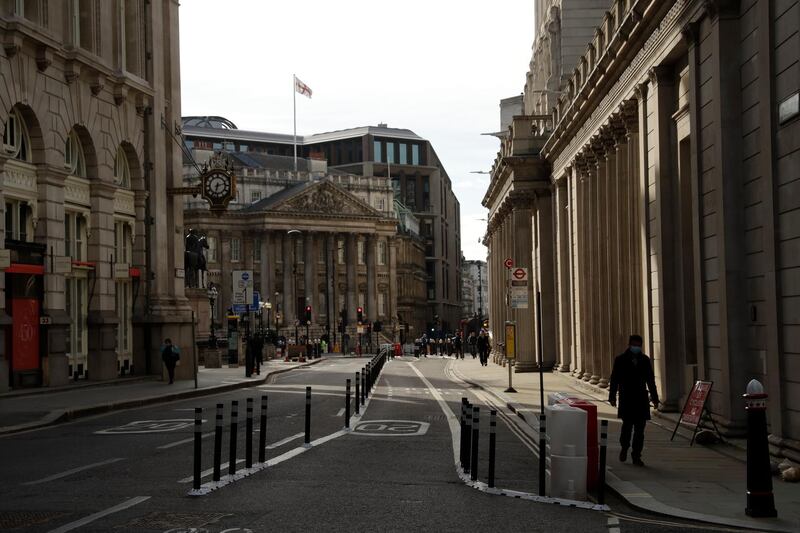 People walk past the Bank of England in a quiet City of London financial district. AP Photo