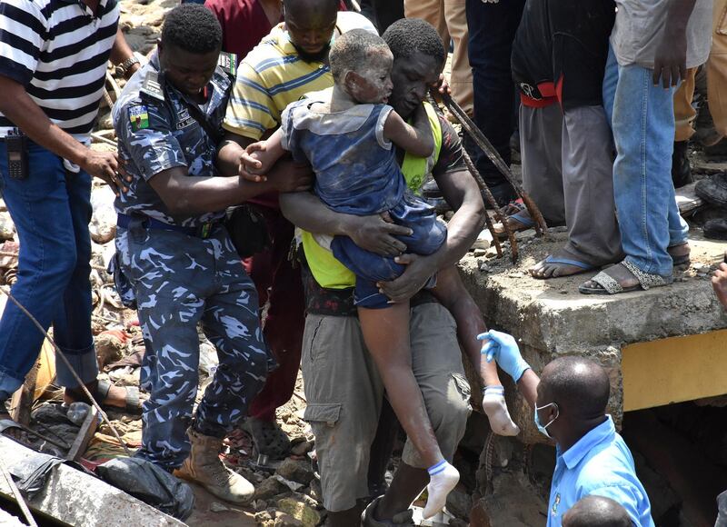 epa07434635 Rescue workers carry a child rescued from the ruble at the scene of a building collapse in Ita Faji, Lagos, Nigeria, 13 March 2019. Reports indicate the three story building contained a primary school on its top floor. Rescue workers are working to free trapped pupils from the rubble.  EPA/STR