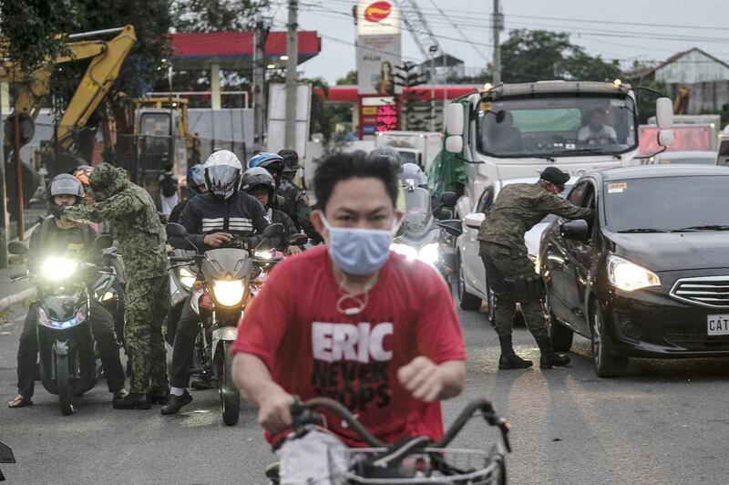 Members of the Philippine Army wearing protective masks take the temperature of travelers entering into Metro Manila. Bloomberg