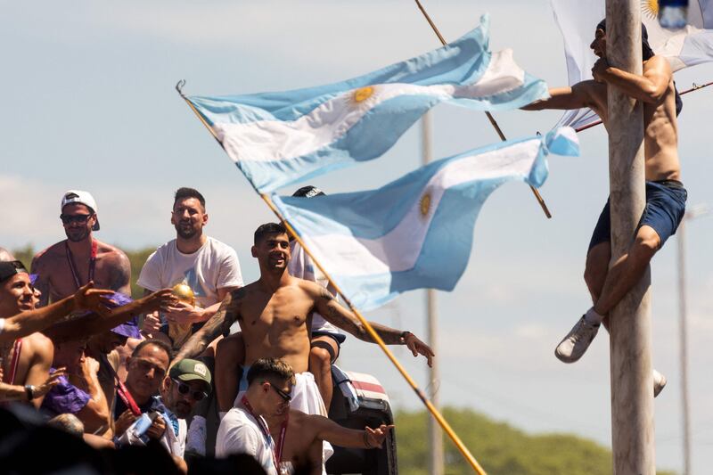 A fan of Argentina clings to a pole cheers as the team passes on the bus. AFP