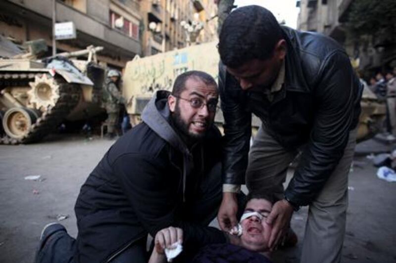 An injured anti-government protester is administered first aid in front of army vehicles during clashes in Tahrir, or Liberation square, in Cairo, Egypt, Wednesday, Feb. 2, 2011. Several thousand supporters of President Hosni Mubarak clashed with anti-government protesters as Egypt's upheaval took a dangerous new turn. (AP Photo/Tara Todras-Whitehill)