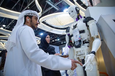 A man interacting with a robot inside Abu Dhabi Government stand at Gitex.  Leslie Pableo / The National