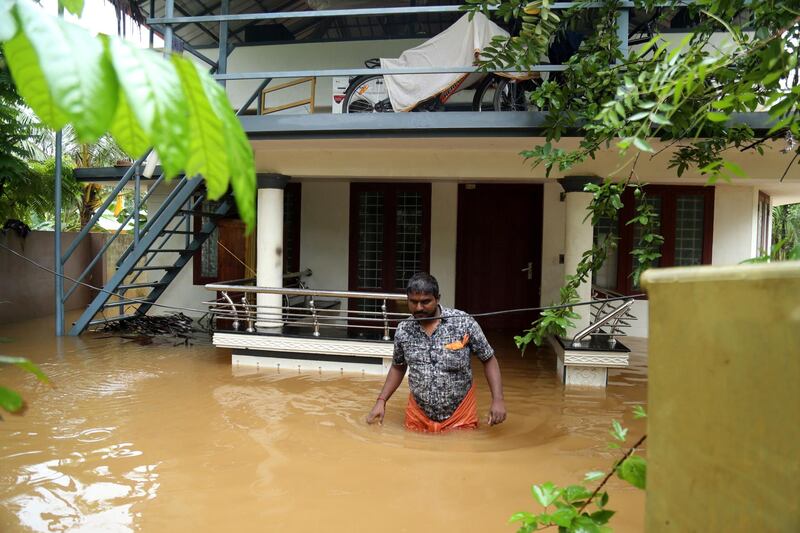 epa07763639 An Indian man walks in a flooded street outside a house in Kochi, Kerala, India, 09 August 2019. According to news reports, the operation of the Cochin International Airport has been stopped till 11 August after Heavy rains saw water levels rise in the Periyar river, near Cochin airport.  EPA/PRAKASH ELAMAKKARA