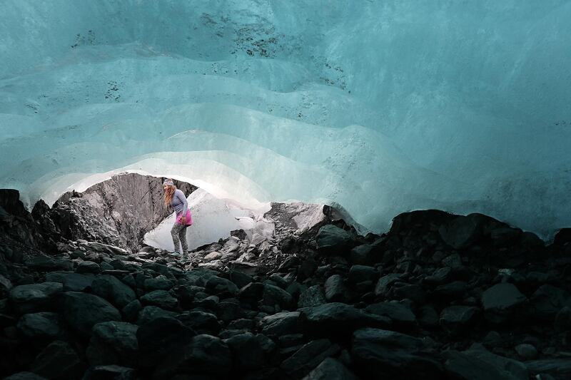 Emily Baker, a Geophysicist with the United States Geological Survey, walks past the mouth of an ice cave carved out underneath the Wolverine Glacier in the Kenai Mountains near Primrose, Alaska.  AFP