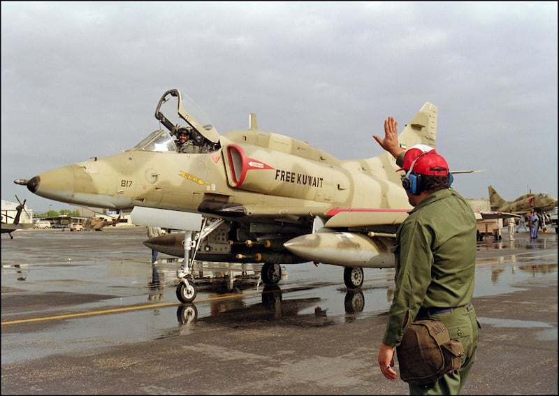 A Kuwaiti airfield worker waves to a departing of a Kuwaiti Air Force A-4 US-made Skyhawk jet fighter pilot 24 January 1991 leaving the Al Hasra air base for a bombing mission over Iraq. Iraq's invasion of Kuwait 02 August 1990, ostensibly over violations of the Iraqi border, led to the Gulf War which began 16 January 1991. A US-led multi-national force expelled Iraq from Kuwait during the "Desert Storm" offensive and a cease-fire was signed 28 February 1991. (Photo by CHRIS WILKINS / AFP)