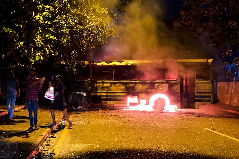 People gather near a burning bus in Colombo. AFP