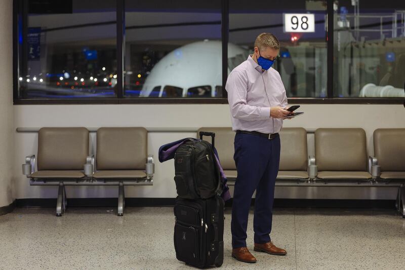 A passenger wearing a protective mask looks at his phone at Newark Liberty International Airport in Newark, New Jersey, U.S. From November 16 through December 11, the United Airlines will offer rapid tests to every passenger over 2 years old and crew members on board select flights from Newark Liberty International Airport to London Heathrow, free of charge. Bloomberg