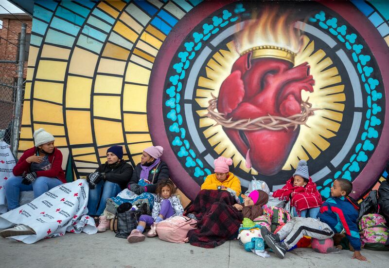 Migrants try to stay warm while camping outside the church. AP