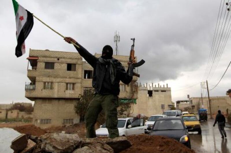 A Syrian soldier, who has defected to join the Free Syrian Army, holds up his rifle and waves a Syrian independence flag in the Damascus suburb of Saqba January 27, 2012. A small green, white and black rebel flag waving at the entrance to Saqba showed it was no longer under the control of President Bashar al-Assad's forces.  REUTERS/Ahmed Jadallah    (SYRIA - Tags: CIVIL UNREST POLITICS TPX IMAGES OF THE DAY) *** Local Caption ***  AJS01_SYRIA-TOWN-_0127_11.JPG
