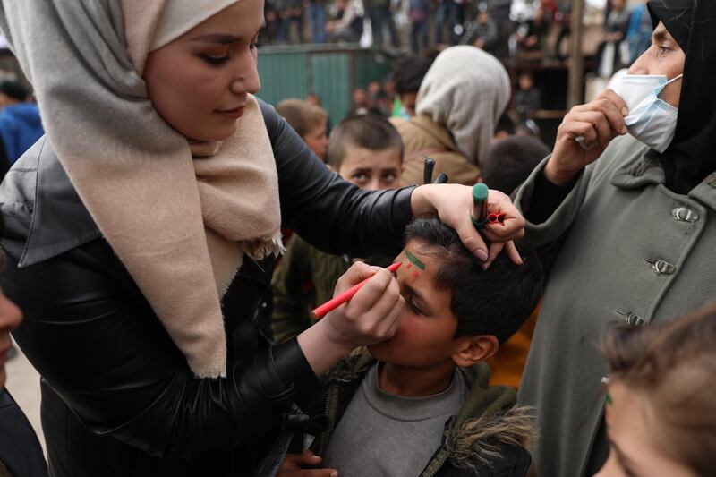 A woman draws a flag on a boy's head as they are gathered to commemorate the ten years anniversary of the uprising against the Syrian government, Idlib. EPA
