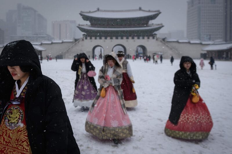 Visitors wearing traditional hanbok dress walk through Gyeongbokgung palace during snowfall in central Seoul, South Korea. AFP