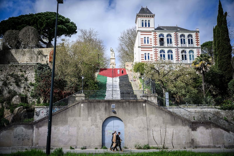 People pass by a giant Palestinian flag painted on stairs, in the centre of Nantes. AFP
