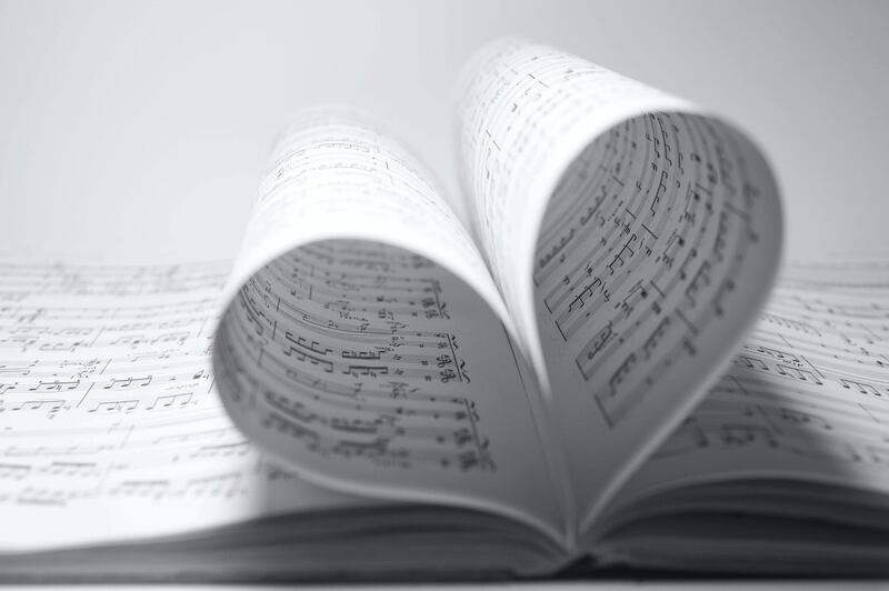 Sheet music bending into a heart shape.