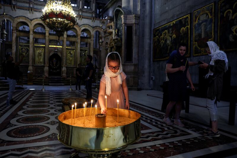 A girl places a candle in the church.