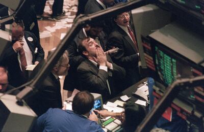 A trader (c) on the New York Stock Exchange looks at stock rates 19 October 1987 as stocks were devastated during one of the most frantic days in the exchange's history.  The Dow Jones index plummeted over 200 points in record trading. (Photo by MARIA BASTONE / AFP)