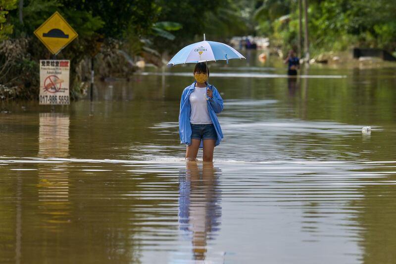 A woman walks along a road submerged by floodwaters following heavy monsoon rains in Mentakab town in Malaysia's Pahang state.  AFP