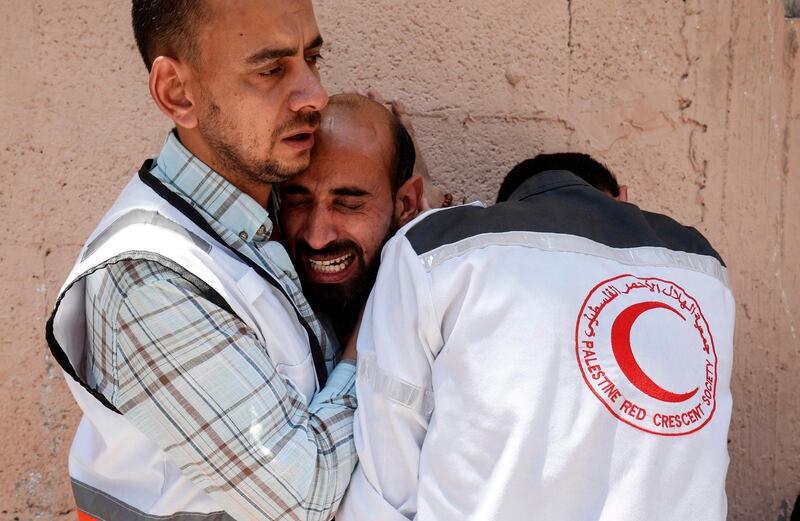 TOPSHOT - Co-workers of paramedic Mohammed al-Jdaili, who succumbed to his wounds a month after being shot during clashes along the Gaza border, mourn during his funeral in the Bureij refugee camp, in the central Gaza Strip on June 11, 2019. The Palestinian Red Crescent organisation said in a statement that 36-year-old Jdaili had been hit in the face by a rubber-coated bullet "while performing his humanitarian duties" in northern Gaza on May 3. / AFP / SAID KHATIB
