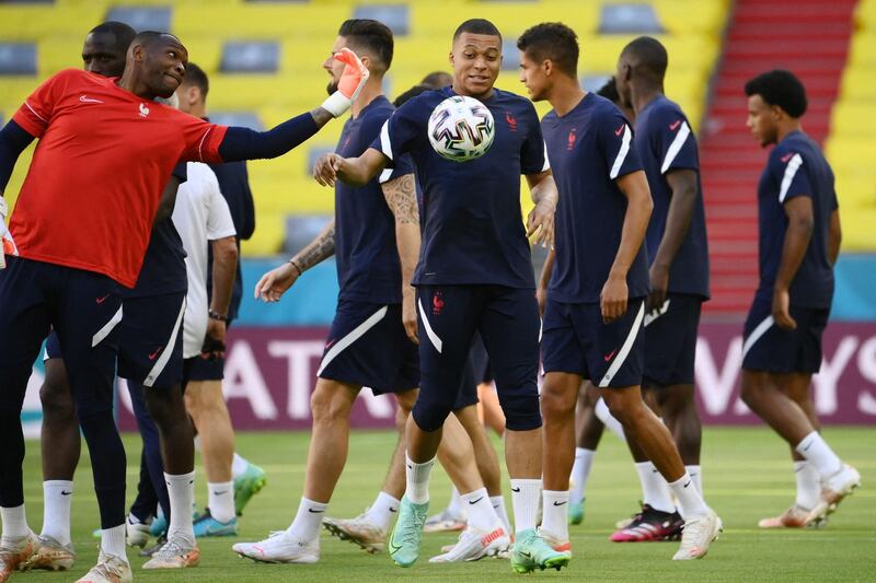 France's goalkeeper Steve Mandanda (L) and France's forward Kylian Mbappe (C) attend an MD-1 training session at the Allianz Arena in Munich on June 14, 2021, on the eve of their UEFA EURO 2020 football match against Germany. / AFP / FRANCK FIFE
