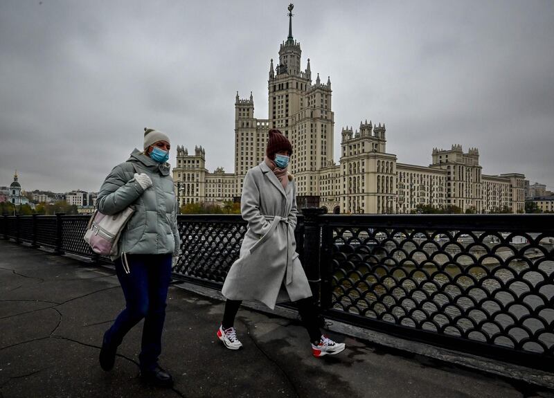 Two women wearing face masks to protect against coronavirus walk along a bridge near a Stalin-era skyscraper in central Moscow, Russia. AFP