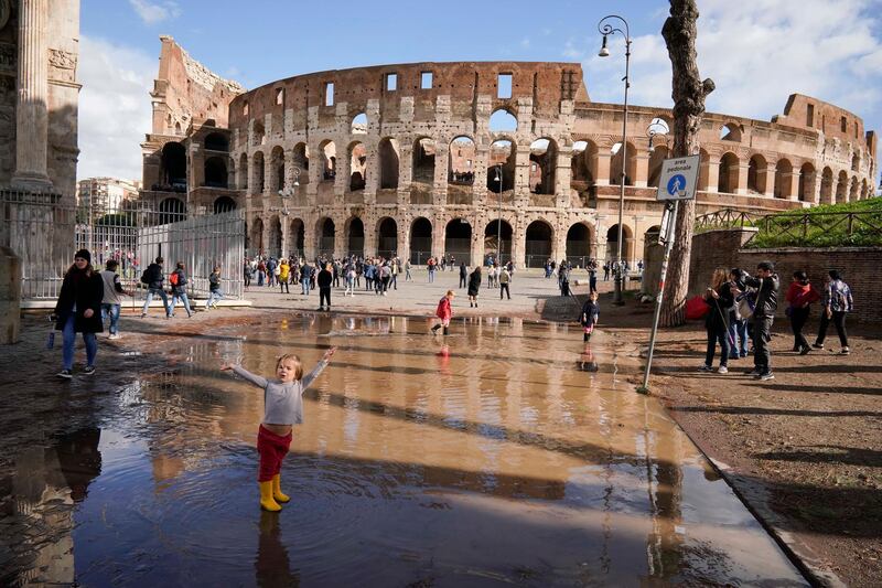 A child plays in a puddle by the ancient Colosseum a day after strong winds and rain hit the city, in Rome, Tuesday, Oct. 30, 2018. The national Civil Protection Agency has issued red and orange alerts -- meaning possible "loss of life" from landslides, floods, and infrastructural damage -- due to an Atlantic storm system that has brought torrential rains and hail, electrical storms, powerful winds and high seas to Italy from North to South. (AP Photo/Andrew Medichini)