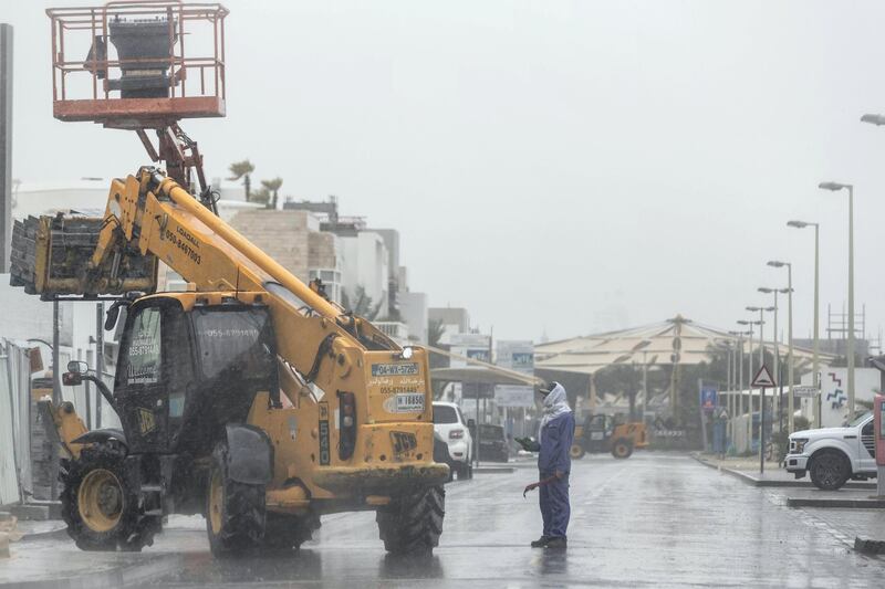 DUBAI, UNITED ARAB EMIRATES. 15 APRIL 2020. Rain pours down in Dubai. A construction worker in the rain on Kite Beach. (Photo: Antonie Robertson/The National) Journalist: STANDALONE. Section: National.