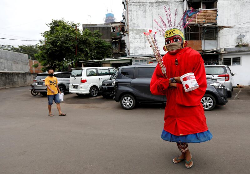 Putra, a 15-year-old performer wearing a large puppet figure called "Ondel-ondel", donning a face mask, walks on a street during a performance at a densely residential area in Jakarta, amid the spread of coronavirus disease in Indonesia. Reuters