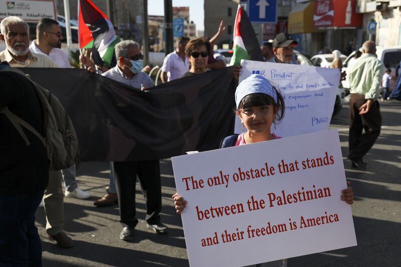 A Palestinian protester carries a placard during a demonstration in the occupied West Bank city of Ramallah as US President Joe Biden visited Israel. AFP