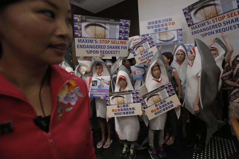 A Chinese restaurant attendant, left, stands next to a group of animal conservation activists wearing shark outfits during a protest outside a restaurant in Hong Kong. Kin Cheung / AP Photo