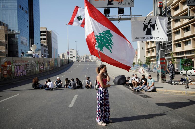 A woman holds a Lebanese flag as she stands at a roadblock during ongoing anti-government protests in Beirut. Reuters