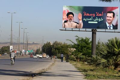 A billboard with pictures of Iranian President Ibrahim Raisi (L) and Syrian President Bashar Al Assad stands on the road leading to Damascus International Airport. AFP