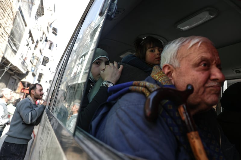 An elderly man with two girls sit inside a bus during the evacuation in rebel-held Douma, Syria, on March 17, 2018. Mohammed Badra / EPA