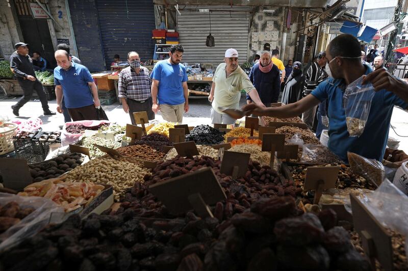 A vendor wearing a protective face mask serves customers at his shop in Amman, Jordan. Reuters