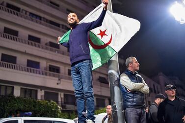 An Algerian man stands with a national flag celebrating the news that president Abdelaziz Bouteflika will not seek re-election. AFP