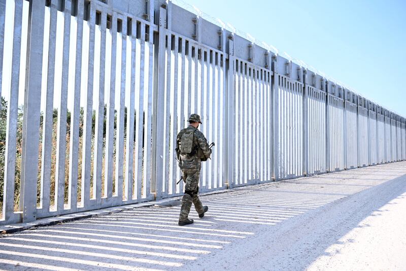 A soldier patrols a steel fence built along the Evros river in Feres, Greece, at the Turkish border.  EPA