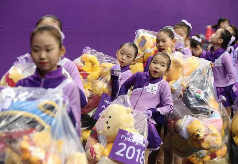Flower girls collect tens of yellow Winnie-the- Pooh bears thrown on the ice after top-scorer Yuzuru Hanyu of Japan competed in the Short Program of the Figure Skating Men Single competition at the Gangneung Ice Arena.  Tatyana Zenkovich / EPA