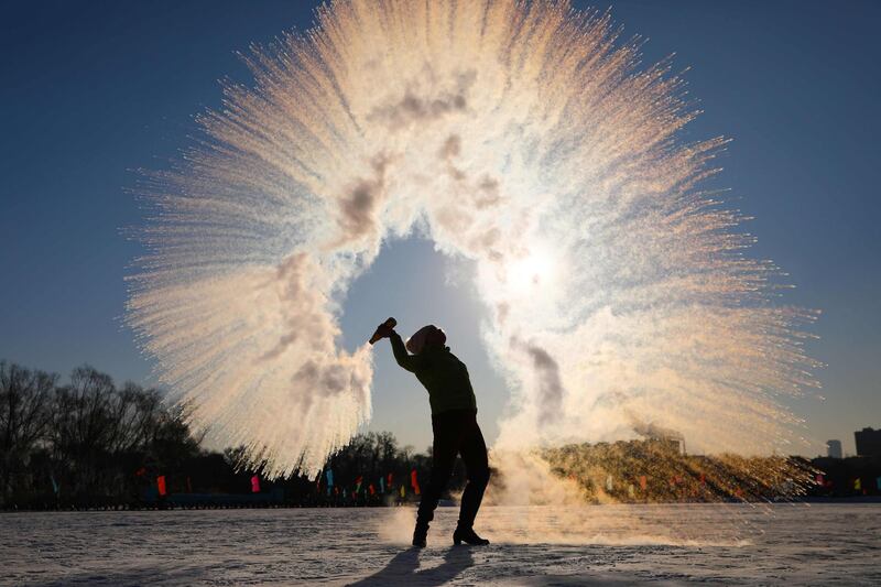 A woman throws hot water into the air, which instantly condenses into ice crystals amid temperatures of minus 27 degrees Celsius, in Shenyang in northeastern China's Liaoning province.  AFP
