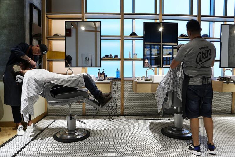 Dan Mellor, left, a barber at Akin Barber & Shop in Dubai, grooming a customer’s beard. On the cover: Mellor trims Bill Tibor’s beard. Pawan Singh / The National 