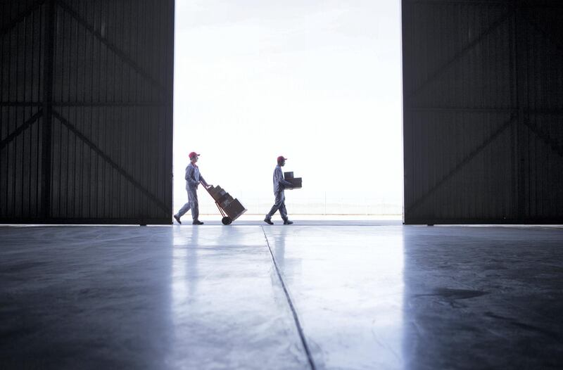 Two couriers working together to deliver parcels and boxes outside a warehouse door