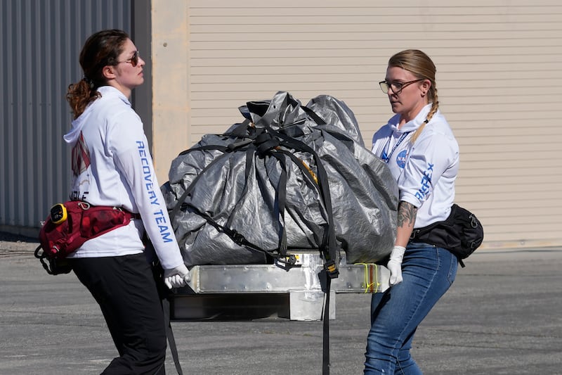 Recovery team members carry a capsule containing Nasa's first asteroid samples to a temporary clean room at Dugway Proving Ground in Utah. AP
