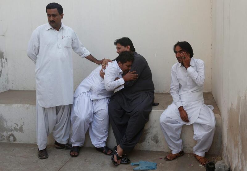 Men mourn the death of their relatives at a morgue after the fire. Akhtar Soomro / Reuters