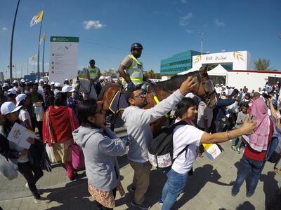 Attendees of Pope Francis's Mass at Zayed Sports City take pictures with police horses. Pawan Singh