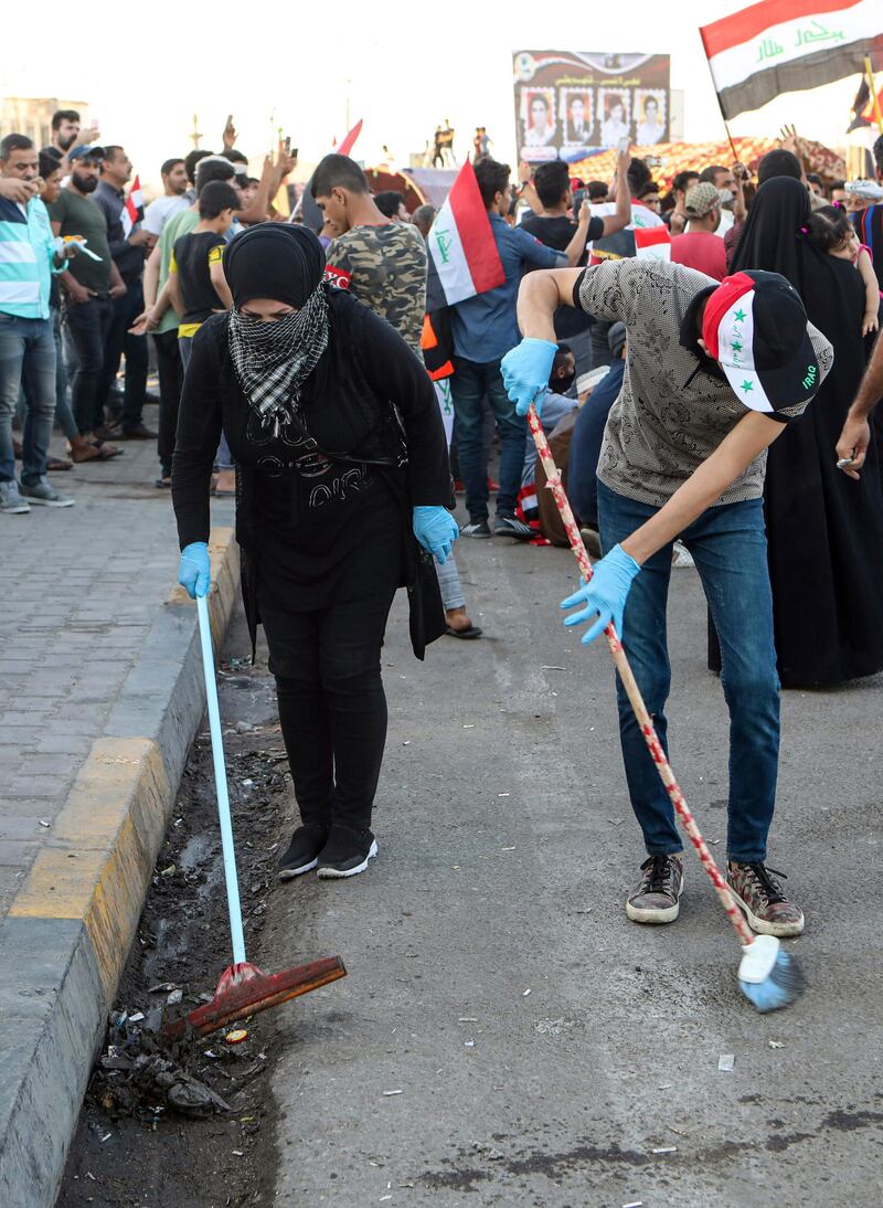 Volunteers clean the site of the protest near the Basra provincial council building during protests in the city. AP