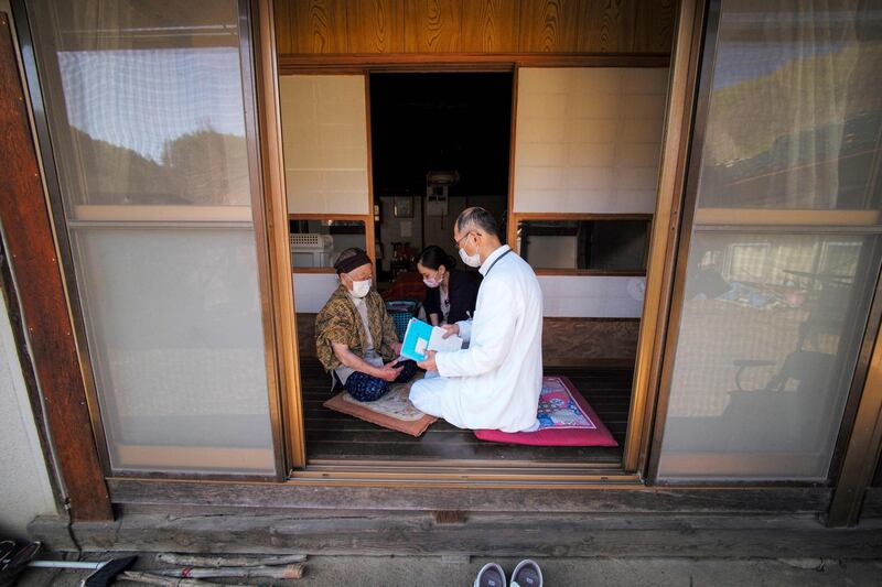 A health worker provides medical care to Kakino Yamaguchi, left, after inoculating her with the Pfizer-BioNTech Covid-19 vaccine in her home in Kitaaiki village in Nagano Prefecture, Japan, on April 21, 2021. AFP