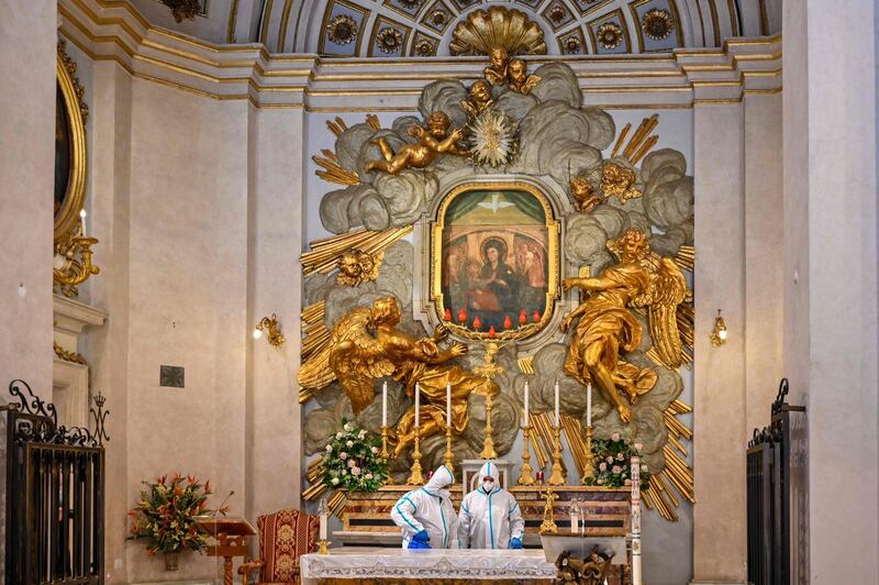 Employees of Rome's Municipal Environment Company (AMA), wearing protective overall and mask, sanitize the Santuario della Madonna del Divino Amore church in the southern Castel di Leva district of Rome.  AFP