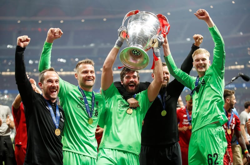 Alisson lifts the trophy with teammates. Reuters
