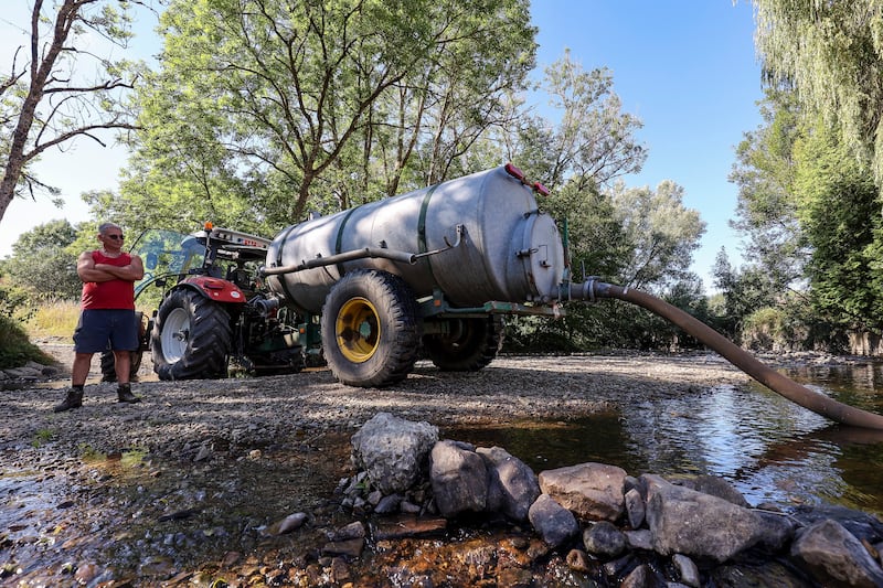 A farmer pumps water in a river near Wellin, southern Belgium. EPA