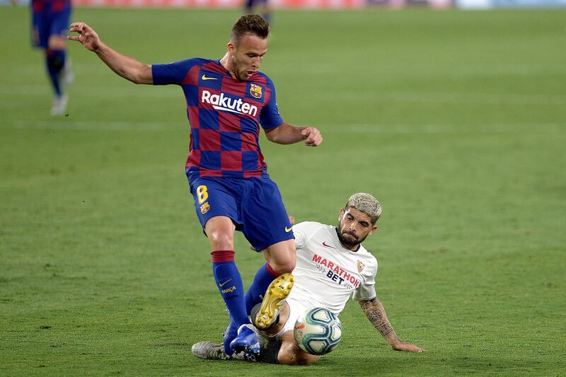 Sevilla's Argentinian midfielder Ever Banega (R) challenges Barcelona's Brazilian midfielder Arthur (L) during the Spanish league football match between Sevilla FC and FC Barcelona at the Ramon Sanchez Pizjuan stadium in Seville on June 19, 2020. (Photo by CRISTINA QUICLER / AFP)